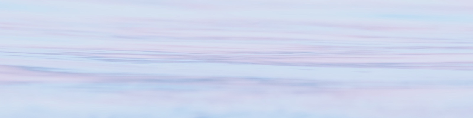 Close up of water surface that reflects multiple colours of light pink, purple and blue.