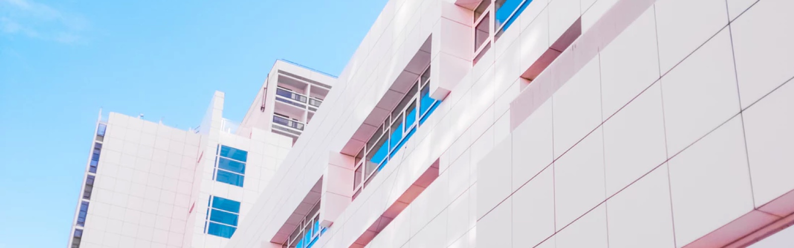 Side view of a large, tall and pink building with dark windows.