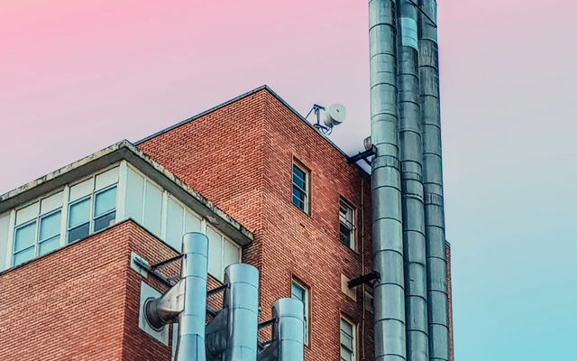 Side view of a red brick industrial looking building against a pink sky.